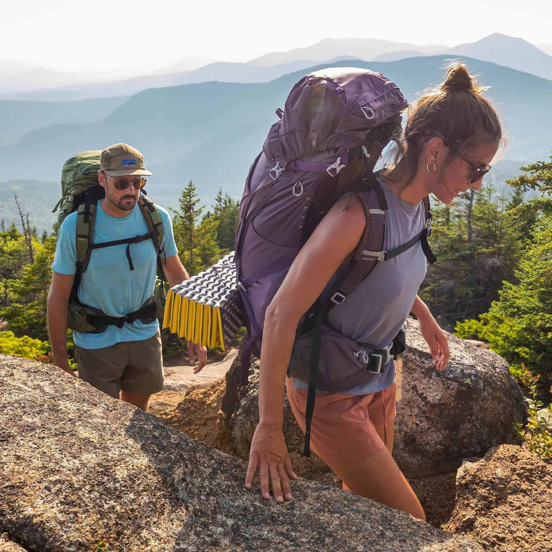 Couple climbing up mountain with daypacks on back