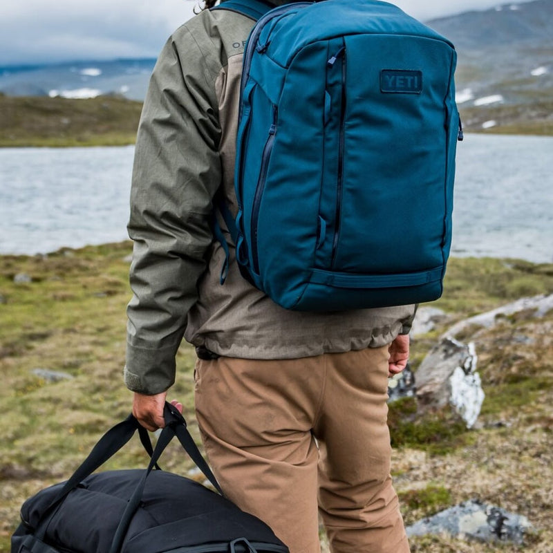 Blue backpack on man standing in front of river