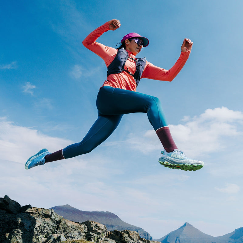 Photo of woman celebrating in the air with Hoka trail shoes on