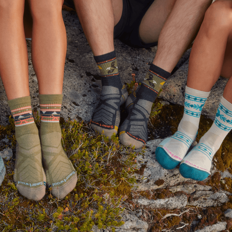 Set of 3 feet sitting their feet on mossy rocks with colorful socks