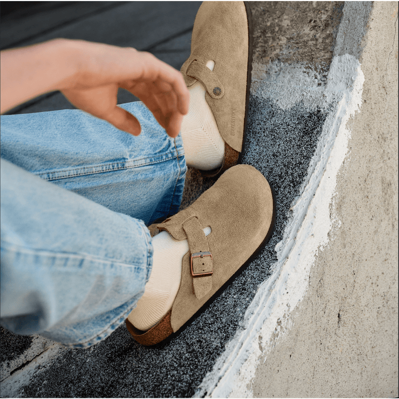Photo of man sitting on ledge. Close up of Birkenstock suede shoes