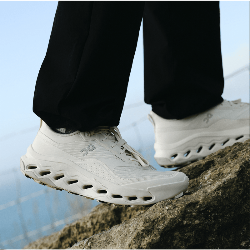 White trail shoes walking up set of rocks with blue background