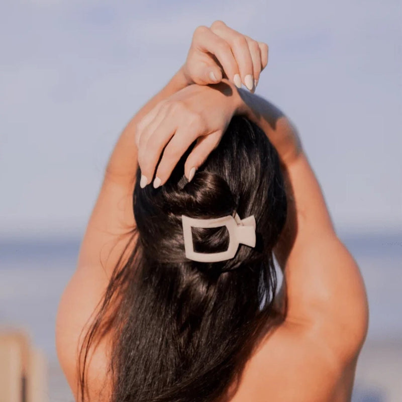 Back of woman's head with hands over head. Hairclip in hair