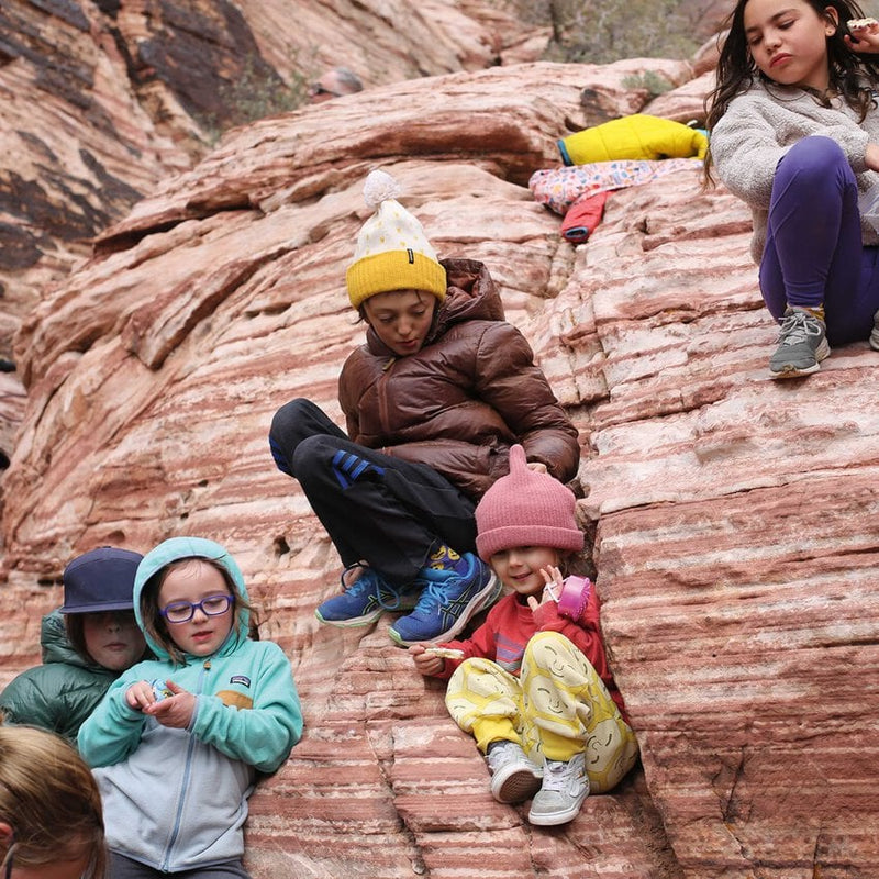 Group of kids sitting on the edge of a Grand Canyon style rockface