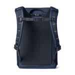 A YETI backpack shown from the back, featuring a dark navy blue padded main compartment with embossed branding, dark blue side panels, and black shoulder straps with silver reflective stitching, set against a plain white background.